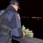 A police officer drops a wreath off the Carson-Nguyen Bridge in honor of two police officers who died 12 years ago on Christmas night. (Image courtesy of Richard J. McCormack and NJ .com)