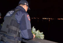 A police officer drops a wreath off the Carson-Nguyen Bridge in honor of two police officers who died 12 years ago on Christmas night. (Image courtesy of Richard J. McCormack and NJ .com)