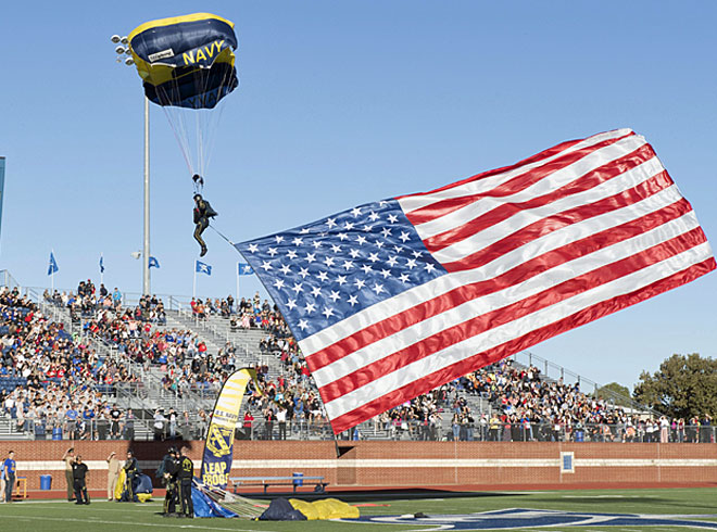 Retired Navy SEAL Jim Woods, aof the U.S. Navy parachute team, the Leap Frogs, presents our nation's flag as he prepares to land during a parachute demonstration as part of Navy Week Fort Worth 2017. Navy Week programs serve as the Navy's principal outreach effort in areas of the country without a significant Navy presence. (Image courtesy of the U.S. Navy by Mass Communication Specialist 3rd Class Danny Kelley)