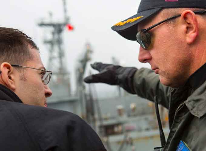 Current Surface Warfare Officers School (SWOS) Commanding Officer Capt. Scott Robertson, then former commanding officer of Ticonderoga-class cruiser USS Normandy (CG 60), speaks with a Sailor while underway. SWOS is reviewing how they train Officers and is collecting information on navigation, seamanship and shiphandling skills sets by conducting officer of the deck competency checks across fleet concentration areas. (Courtesy of the U.S. Navy)