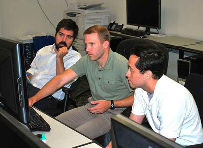 researchers working together inside an U.S. Army Research Laboratory lab to develop greater outcomes in the area of neuroscience. Discussing new results of a recent analysis are (l to r) Dr. Kenneth Ball, postdoctoral researcher, University of Texas at San Antonio; Stephen Gordon, scientist, DCS Corporation; and Vernon Lawhern, statistician, ARL.