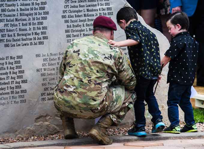 A soldier from the 10th Special Forces helps the sons of Sgt. 1st Class Stephen B. Cribben, Connor, 5, center, and Wyatt, 3, place flowers below their father’s name May 24 during the 15th annual Mountain Post Warrior Memorial Ceremony at Fort Carson in Colorado Springs. Sgt. 1st Class Stephen B. Cribben and Sgt. 1st Class Mihail Golin, green berets for the 10th Special Forces, were honored during the ceremony. (Courtesy of Christian Murdoch, The Gazette)