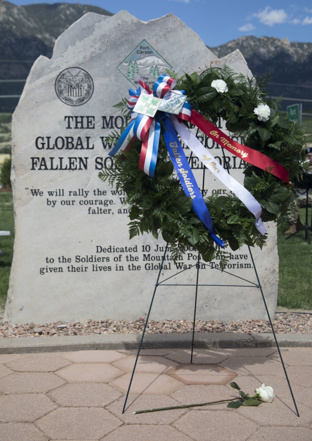 A memorial wreath with two carnations symbolizing Sgt. 1st Class Stephen B. Cribben and Sgt. 1st Class Mihail Golin, two Green Berets assigned to 10th Special Forces Group (Airborne) who were killed in action during operations in Afghanistan, stands in front of the central stone of The Mountain Post Global War on Terrorism Fallen Soldiers Memorial following the Mountain Post Warrior Memorial Ceremony at Fort Carson, Colorado, on May 24, 2018. The annual ceremony serves to honor the memories of Fort Carson Soldiers who’ve lost their lives in operations overseas. (Courtesy of U.S. Army by Sgt. Justin Smith)
