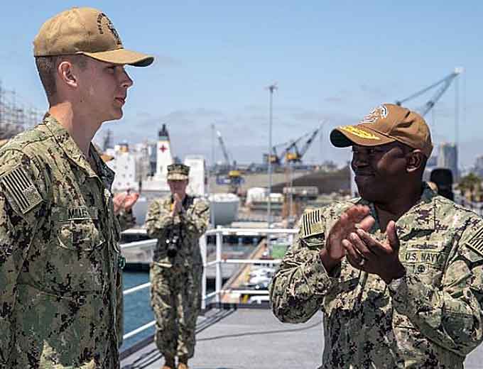 Rear Adm. Cedric Pringle, right, commander of Expeditionary Strike Group (ESG) 3, applauds Religious Programs Specialist Seaman David Miller, from Salem, N.H., assigned to the amphibious assault ship USS Bonhomme Richard (LHD 6), during an awards ceremony on the roof of the barge assigned to Bonhomme Richard. Miller was awarded for his efforts in apprehending a woman threatening a church congregation on April 20, 2019. Bonhomme Richard is in its homeport of San Diego. (Courtesy of the U.S. Navy photo by Mass Communication Specialist Seaman Cosmo Walrath)