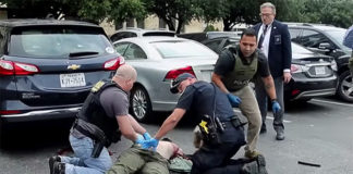 The gunman, identified as Brian Isaack Clyde, was seen on video near the doors to the Earle Cabell Federal Building at about 8:50 a.m. before running across the street and into a parking lot, where he falls down. (Courtesy of The Dallas Morning News, Tom Fox, and YouTube)