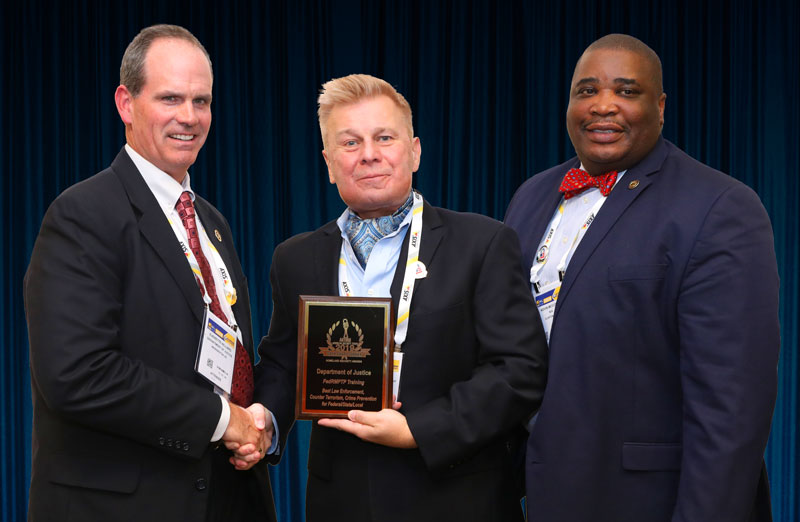 E. Reid Hilliard, Lead and Master Instructor, Assistant Director, Justice Protective Services, Department of Justice (DOJ), and Kevin McCombs, Security Specialist, U.S. Office of Personal Management, accepting one of Four 2019 ‘ASTORS’ Awards at ISC East.
