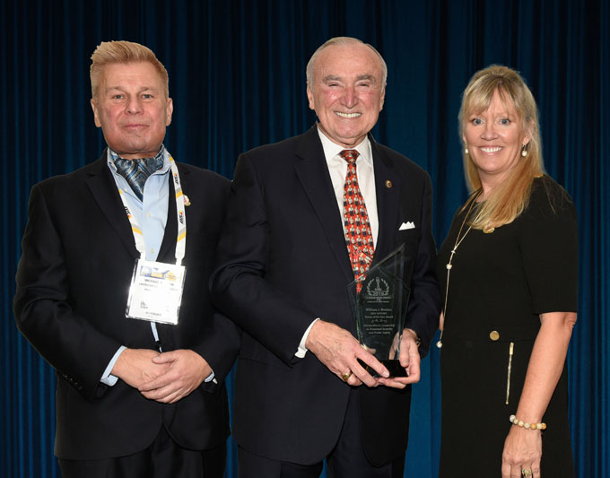 Mike Madsen, AST Publisher (at left); and Tammy Waitt, Managing Director (at right); presenting Commissioner William J. Bratton with his 2019 'ASTORS' Person of the Year Award at the 'ASTORS' Awards Luncheon at ISC East.
