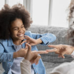 African,Deaf,Kid,Girl,And,Her,Mother,Sitting,On,Couch