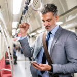 Mature,Businessman,With,Smartphone,In,A,Metro,Train.