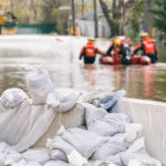 Flood,Protection,Sandbags,With,Flooded,Homes,In,The,Background,(montage)