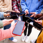 Large,Group,Of,Young,Teenagers,With,Cell,Phones,Standing,In